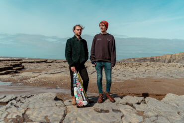 Two males stand on rocks on the beach